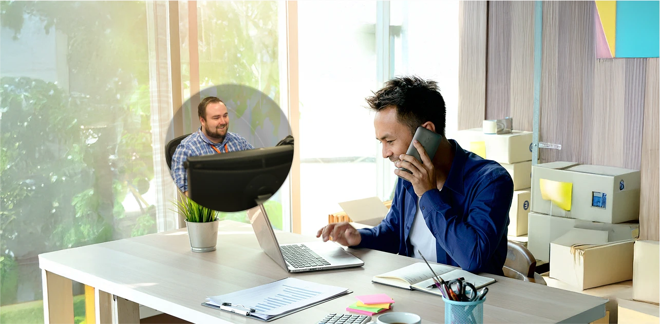 Photo of man talking on a phone to support while working on his laptop